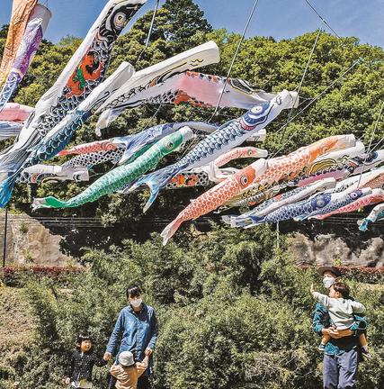 風に吹かれながら悠々と泳ぐこいのぼりを楽しむ家族連れ＝松江市八雲町日吉、日吉親水公園
