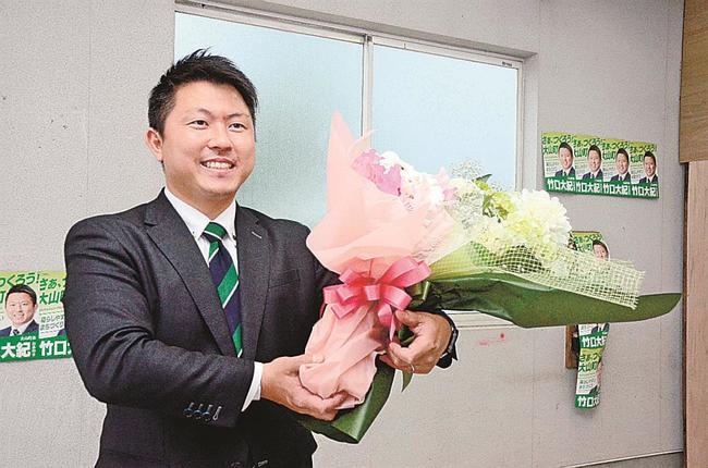 花束を手に再選を喜ぶ竹口大紀氏＝１３日午後５時４０分、鳥取県大山町西坪の事務所
