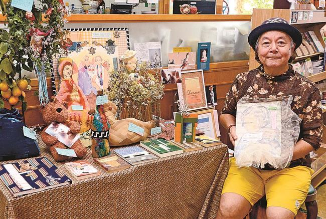 制作した装丁本を手に来場を呼び掛ける長岡哲生さん＝松江市白潟本町、市民活動センター