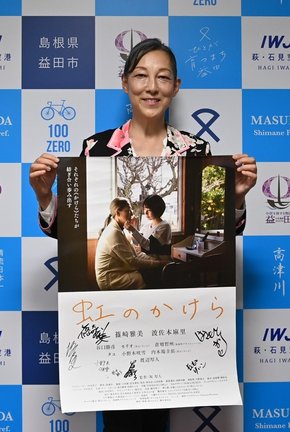 自身が出演している映画「虹のかけら」のポスターを手にする波佐本麻里さん＝益田市常盤町、市役所