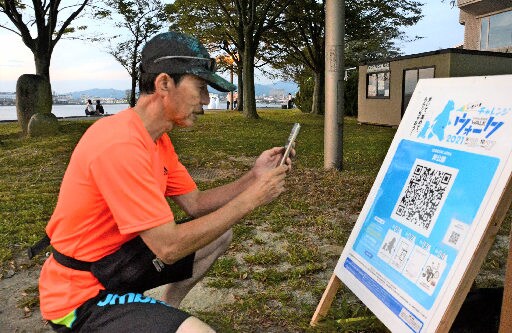 イベントのチェックポイントでＱＲコードを読み込む市民＝松江市袖師町、岸公園