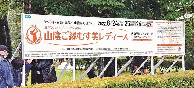 山陰ご縁むす美レディースの開催を知らせる大型看板を設置する関係者＝鳥取県伯耆町丸山、大山平原ゴルフクラブ
