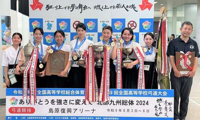 弓道女子団体で初優勝した出雲の選手たち。左から曽田悠葵、飯塚花音、井上心結、宮本佳歩、横山ななみ、高橋心優、古川結楽、宇佐美朝士監督＝長崎県島原市、島原復興アリーナ