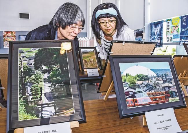 上から見下ろし角度で撮影した一畑電車の写真に見入る来場者＝松江市岡本町、道の駅秋鹿なぎさ公園