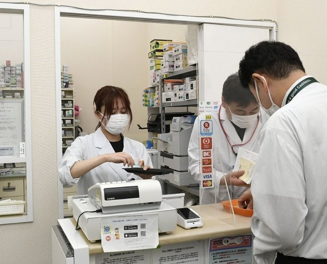 薬剤師から薬を受け取る患者（手前）＝２０２４年６月、東京都内