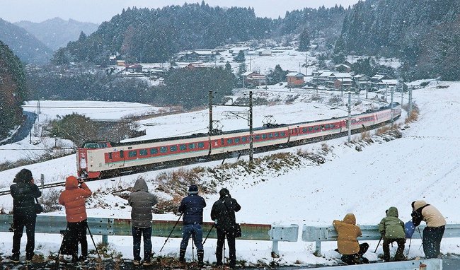 雪景色の中国山地を駆け抜ける３８１系特急やくもを撮影する鉄道ファン＝鳥取県日南町下石見