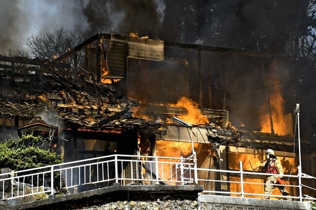 炎を上げる民家＝２７日午後０時５０分、大田市水上町