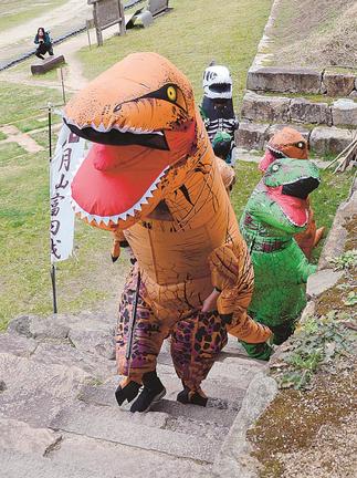 恐竜になりきり月山富田城跡を登る参加者＝安来市広瀬町富田