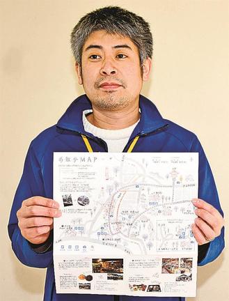 「柴犬の祖石号の里を歩く　お散歩マップ」を手にする小原静伍さん＝益田市美都町宇津川、二川公民館