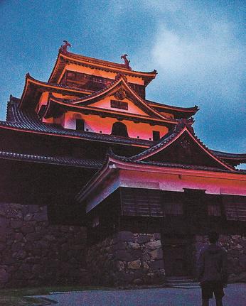 赤色の赤十字カラーにライトアップされた松江城天守＝松江市殿町