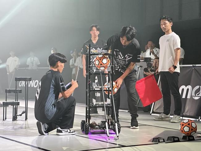 ロボットにボールを装着する学生＝８月24日、広島市西区のモルテン本社