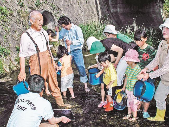 柳生博さん（左）とオオサンショウウオを観察する参加者たち＝２００１年５月、島根県邑南町