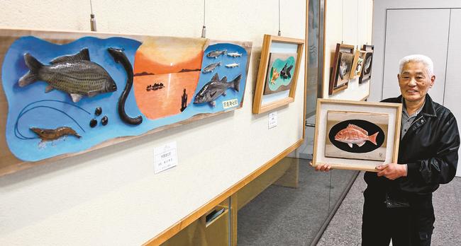 木彫り彩色レリーフ作品を解説する島谷幸吉会長＝松江市御手船場町、しまね信用金庫本店営業部ギャラリー