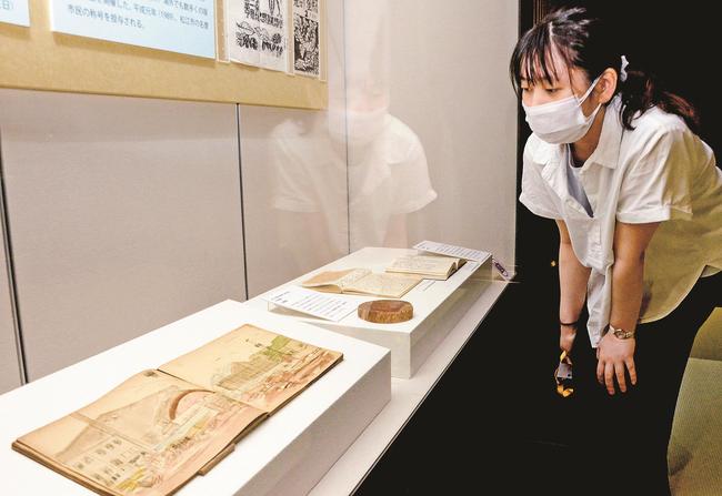 平塚運一が描いた関東大震災後の町並みのスケッチを見る歴史館スタッフ（右）＝松江市殿町、松江歴史館