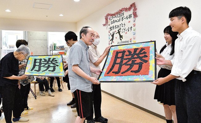 全国高校総体での活躍を願い江津高校ハンドボール部員にボードを贈る入居者ら＝江津市和木町、よろこぼう屋
