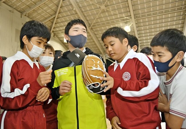 大谷翔平選手から贈られたグラブに触り、感触を確かめる吉田小の児童＝益田市中吉田町