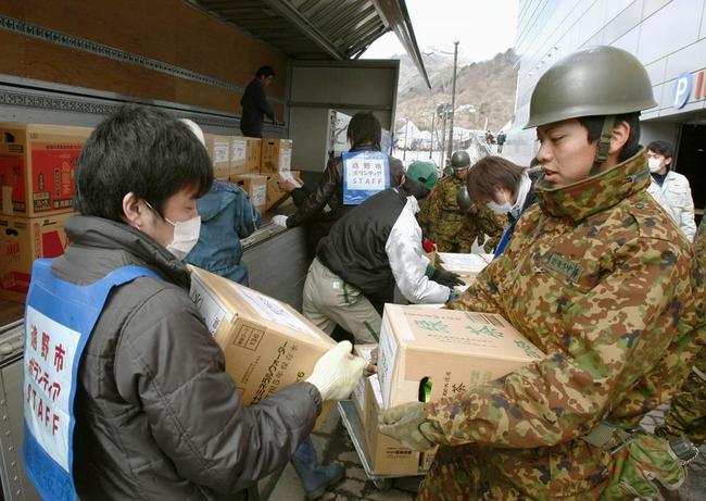 東日本大震災の発生後、トラックで届いた救援物資を運び込むボランティアと自衛隊員ら＝2011年３月23日、岩手県釜石市