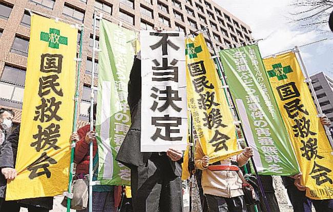 再審開始を認めない決定に、名古屋高裁前で「不当決定」と書かれた紙を掲げる弁護士＝３日
