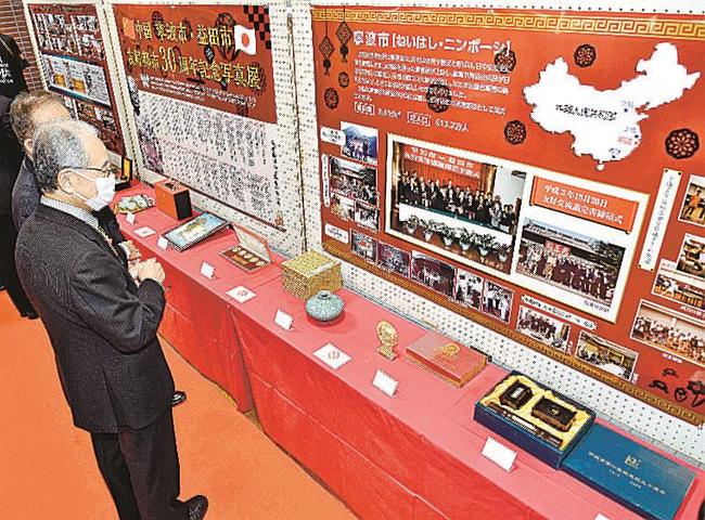 益田市と中国・寧波市の友好交流の歩みを物語る写真や記念品に見入る出席者＝益田市常盤町、市役所