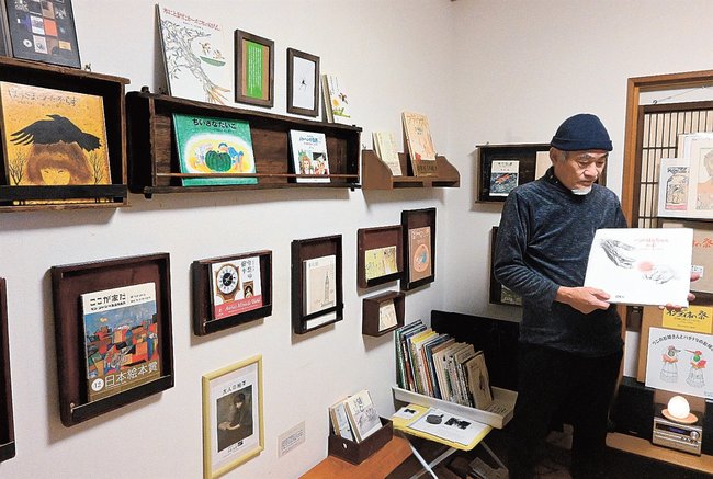 画家が手がけた絵本を紹介する荒川智之さん＝松江市大庭町、沙羅書房