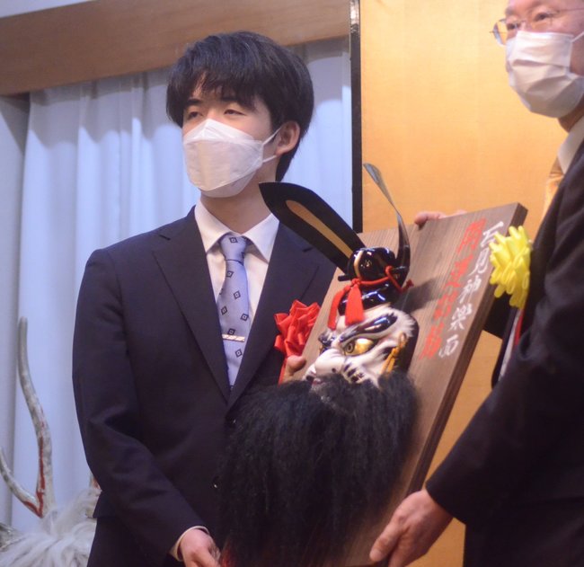 記念品の石見神楽面を受け取る藤井聡太五冠(左)=大田市三瓶町、国民宿舎さんべ荘