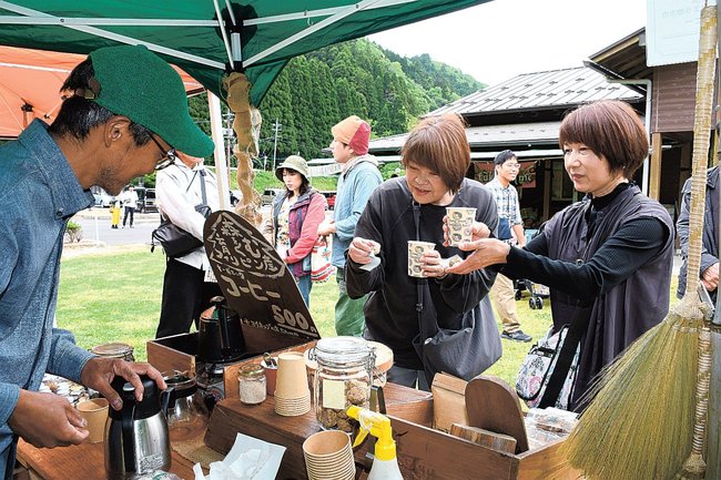 フェアトレードのコーヒーを購入する来場者（右）＝出雲市乙立町、立久恵峡わかあゆの里キャンプ場