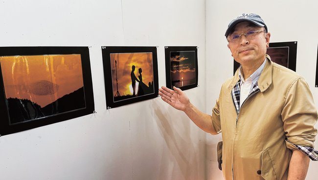 宍道湖で撮影した夕日の写真を紹介する恩田明弘さん＝松江市玉湯町玉造、出雲玉作資料館