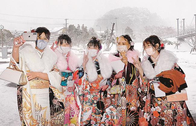 雪を背景に記念撮影する新成人たち＝雲南市三刀屋町古城、アスパル