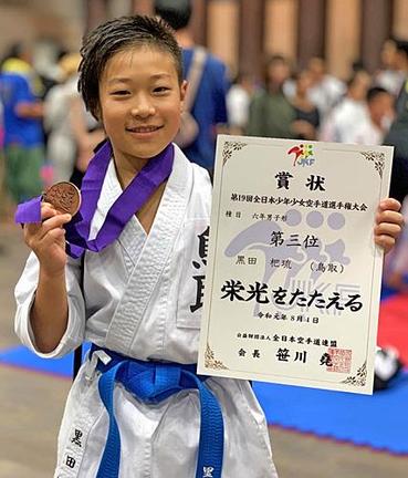 第１９回全日本少年少女空手道選手権大会で３位入賞のメダルと賞状を掲げほほ笑む黒田杷琉君＝２０１９年８月４日、東京都足立区の東京武道館