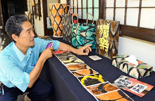 蛇胴を再利用して作ったかばんやティッシュケースを紹介する楫ケ瀬孝さん＝浜田市三隅町古市場、石州和紙会館