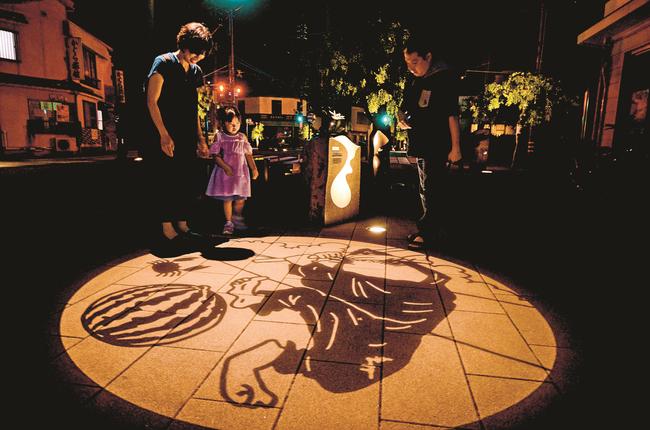 スイカ割りをするねずみ男の妖怪影絵に見入る観光客＝境港市大正町