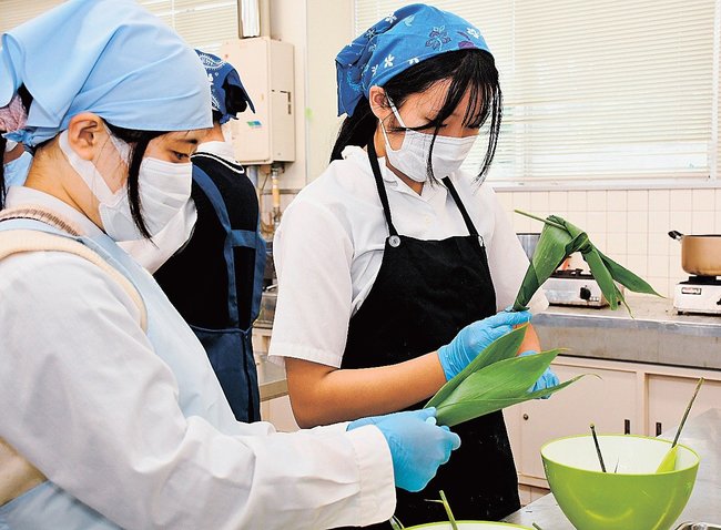 講師のアドバイスを聞いて丁寧にササを巻く生徒＝松江市乃木福富町、松江農林高