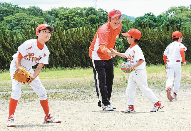 ボールをキャッチできた児童に笑顔でハイタッチする松井慎之介コーチ＝出雲市武志町、斐伊川河川敷公園