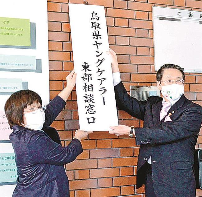 相談窓口の看板を設置する川本由美子所長（左）と平井伸治知事＝鳥取市江津、福祉相談センター
