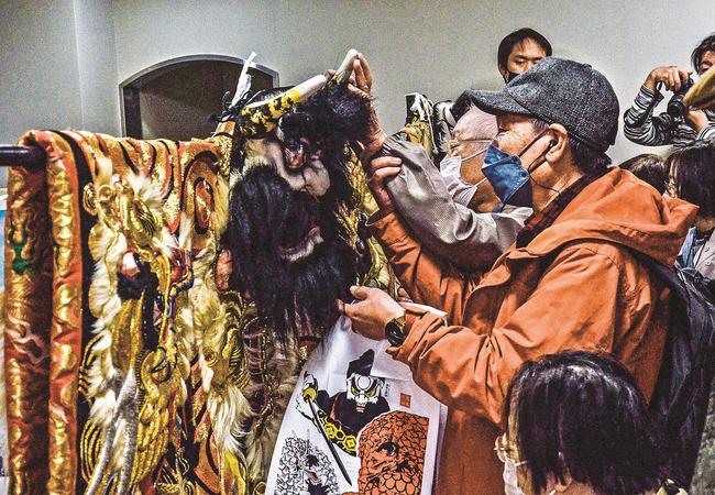 付き添いの手を借りながら石見神楽の衣装に触れる参加者＝益田市駅前町、益田駅前ビルＥＡＧＡ