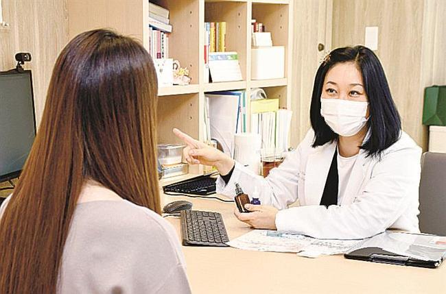 新型コロナウイルスに感染後、脱毛の後遺症に悩む女性（左）を診察する浜中聡子院長＝１０月、東京都千代田区