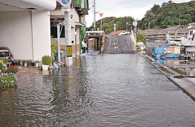 高潮で八尾川の海水があふれて道路が冠水。一部住宅も浸水した＝６日午前８時４８分、島根県隠岐の島町港町