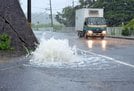 大雨の影響で水が噴き出す道路＝１３日午前１０時３４分、鳥取市福部町内