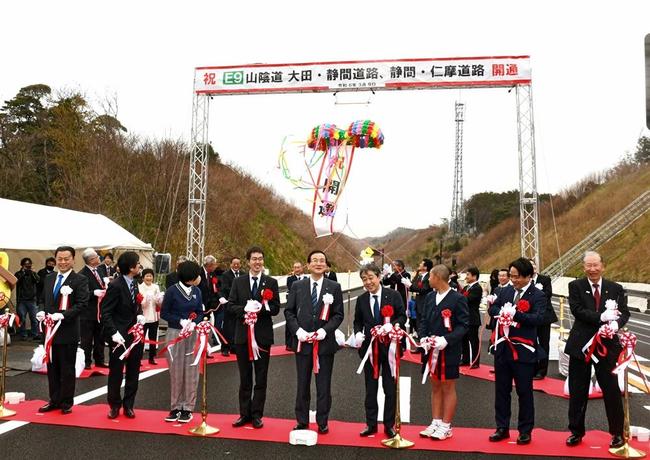 山陰道大田・静間道路と静間・仁摩道路の開通を祝い、テープカットとくす玉割りをする関係者＝９日、大田市静間町の大田静間インターチェンジ付近