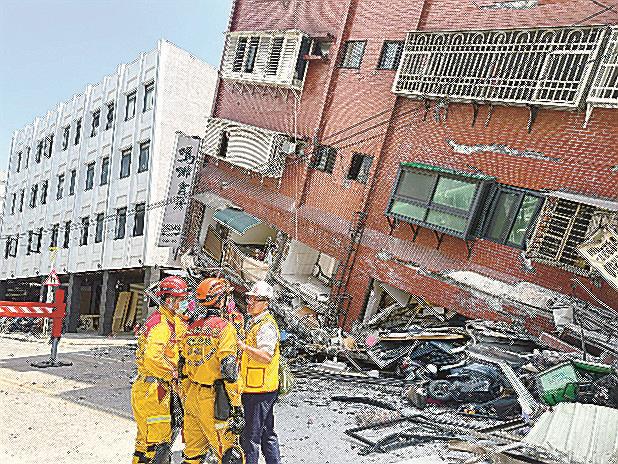 台湾東部花蓮で、倒壊した建物の前に集まる消防隊員ら=3日(台湾消防署提供、共同)