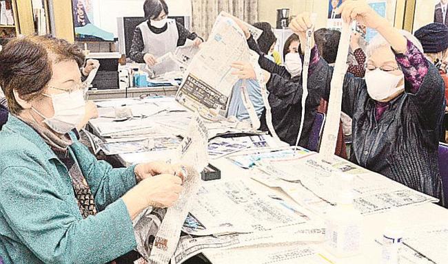本紙を指先で細長く裂く参加者＝浜田市紺屋町