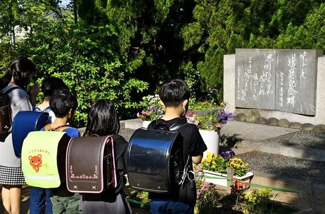 紫雲丸衝突事故の記念碑の前で手を合わせる児童ら＝松江市西川津町、川津小学校