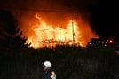 炎を上げる民家と消防士＝11日夜、益田市久城町