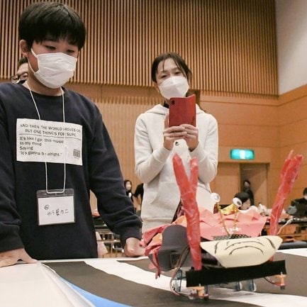 自作のかにロボットの動きを見守る小学生＝松江市朝日町、松江テルサ