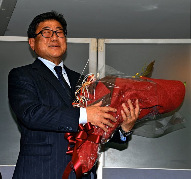 当選確実の報を受け、花束を受け取り笑顔を見せる広田一恭氏＝２７日午後９時０分、倉吉市上井町１丁目の事務所