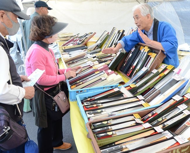 刃物業者の説明を聞きながら品定めをする来場者＝安来市安来町、和鋼博物館