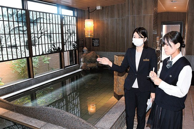 大浴場で従業員（左）の説明を受けながら学ぶ生徒＝雲南市三刀屋町三刀屋