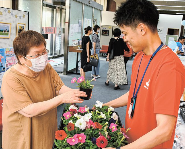 職員から花を受け取る来店者（左）＝出雲市今市町、島根中央信用金庫本店
