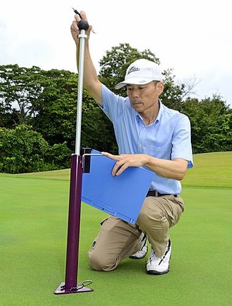 硬度計を使ってグリーン上の芝生の硬度を測る飯塚勉さん＝いづも大社カントリークラブ