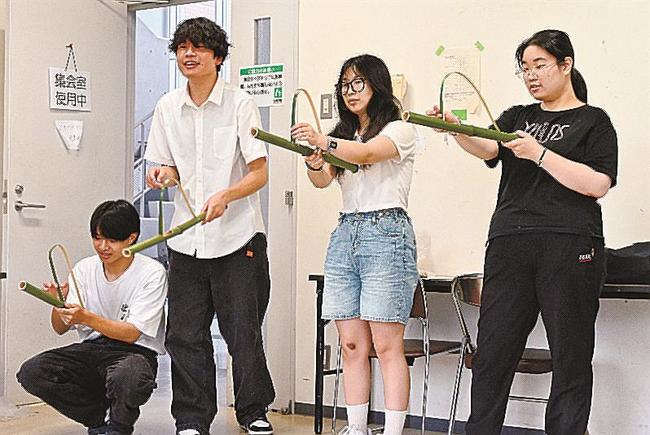 竹を使ったパチンコで木の実を飛ばす学生＝浜田市野原町、島根県立大浜田キャンパス